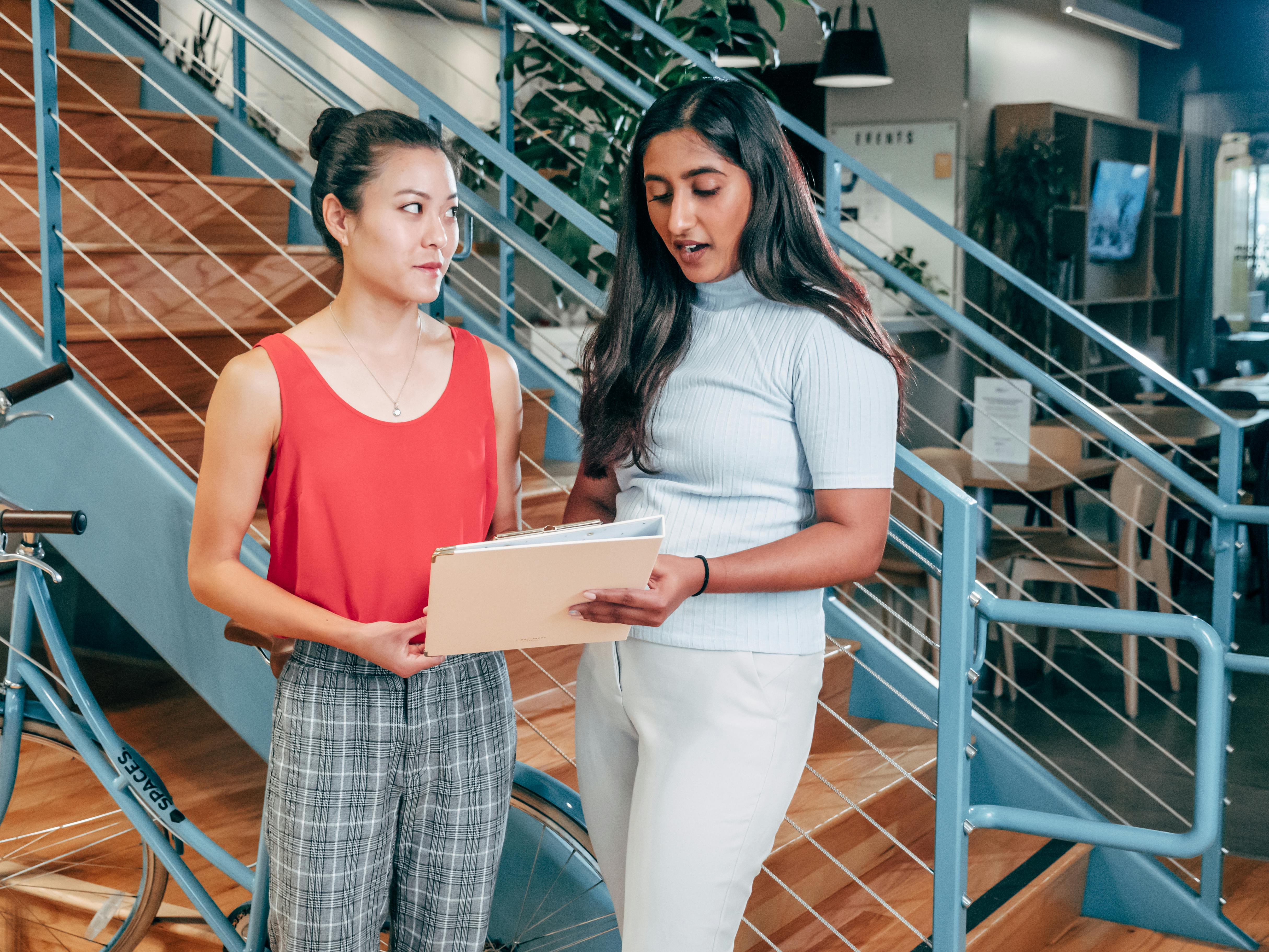Two people talking over a document brief near the bottom of a stairwell