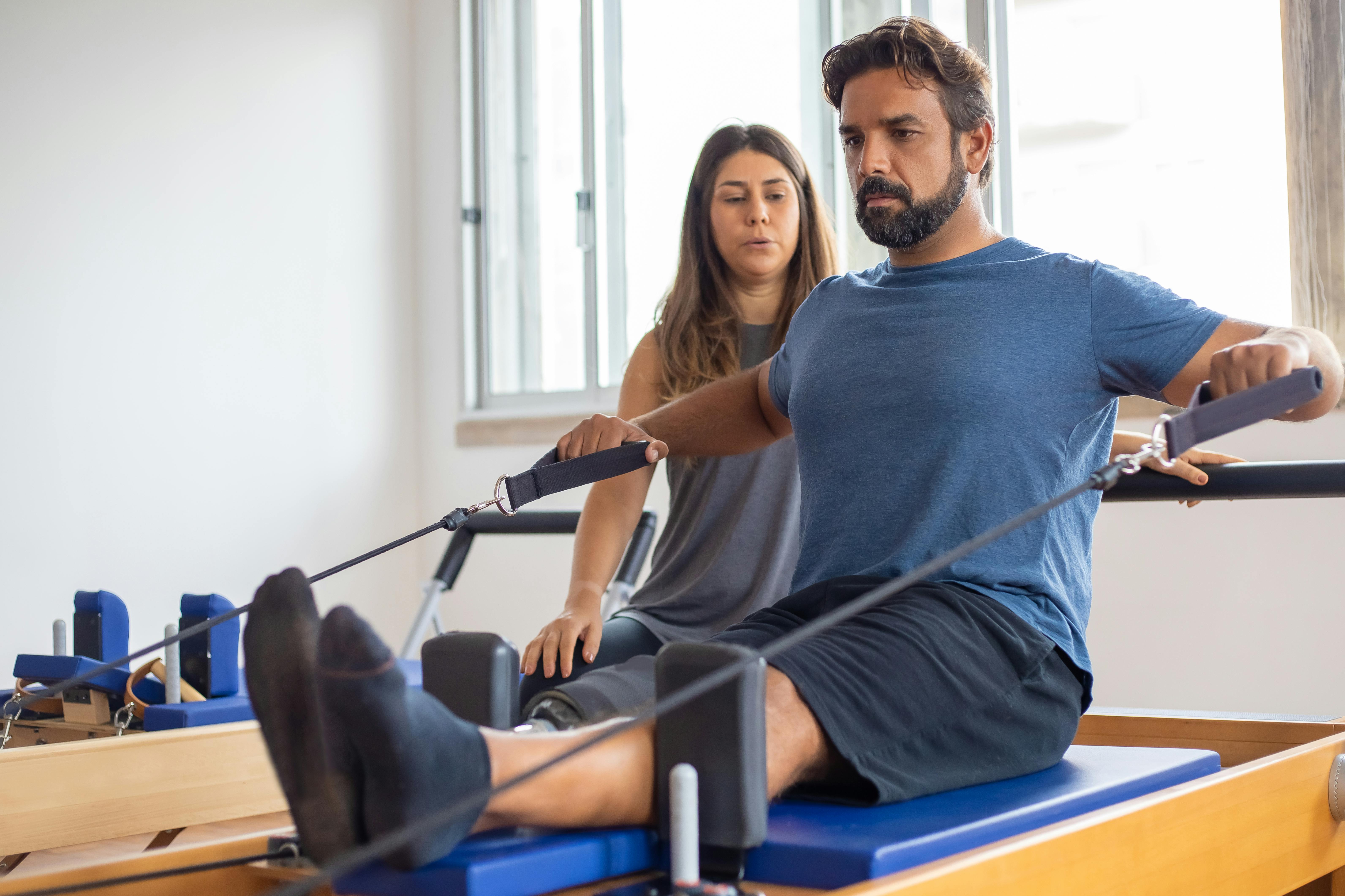 Man stretching with resistance bands, with assistance from a professional.